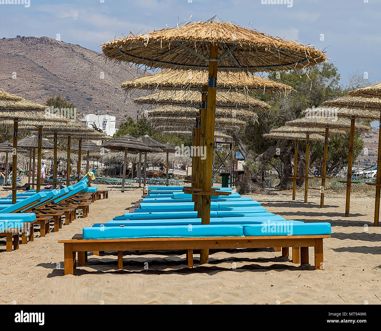 Servizio spiaggia con ombrelloni e sedie a sdraio sulla spiaggia pubblica in Agathopes, in Syros Island. Immagine di stock. Foto Stock