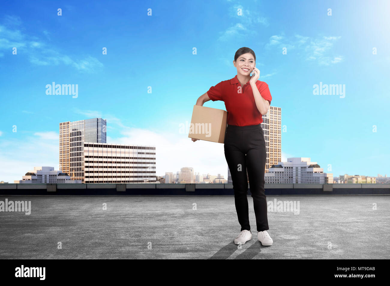 Giovani asiatici donna consegna con pacchetto parlando al cellulare sulla città Foto Stock