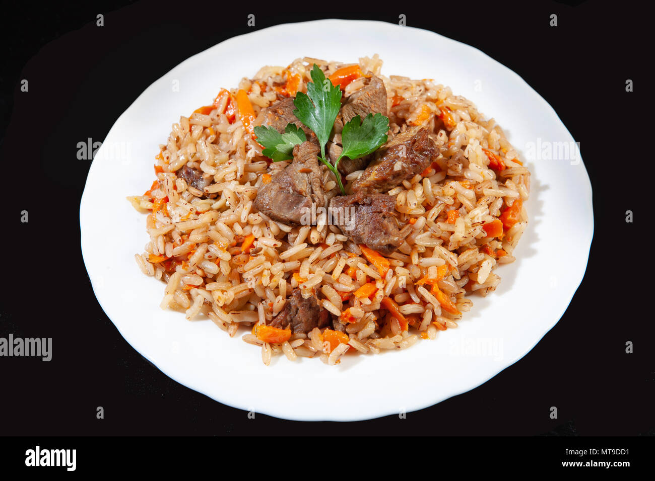 Piastra con un cibo asiatico pilaw su un nero di sfondo per studio Foto Stock