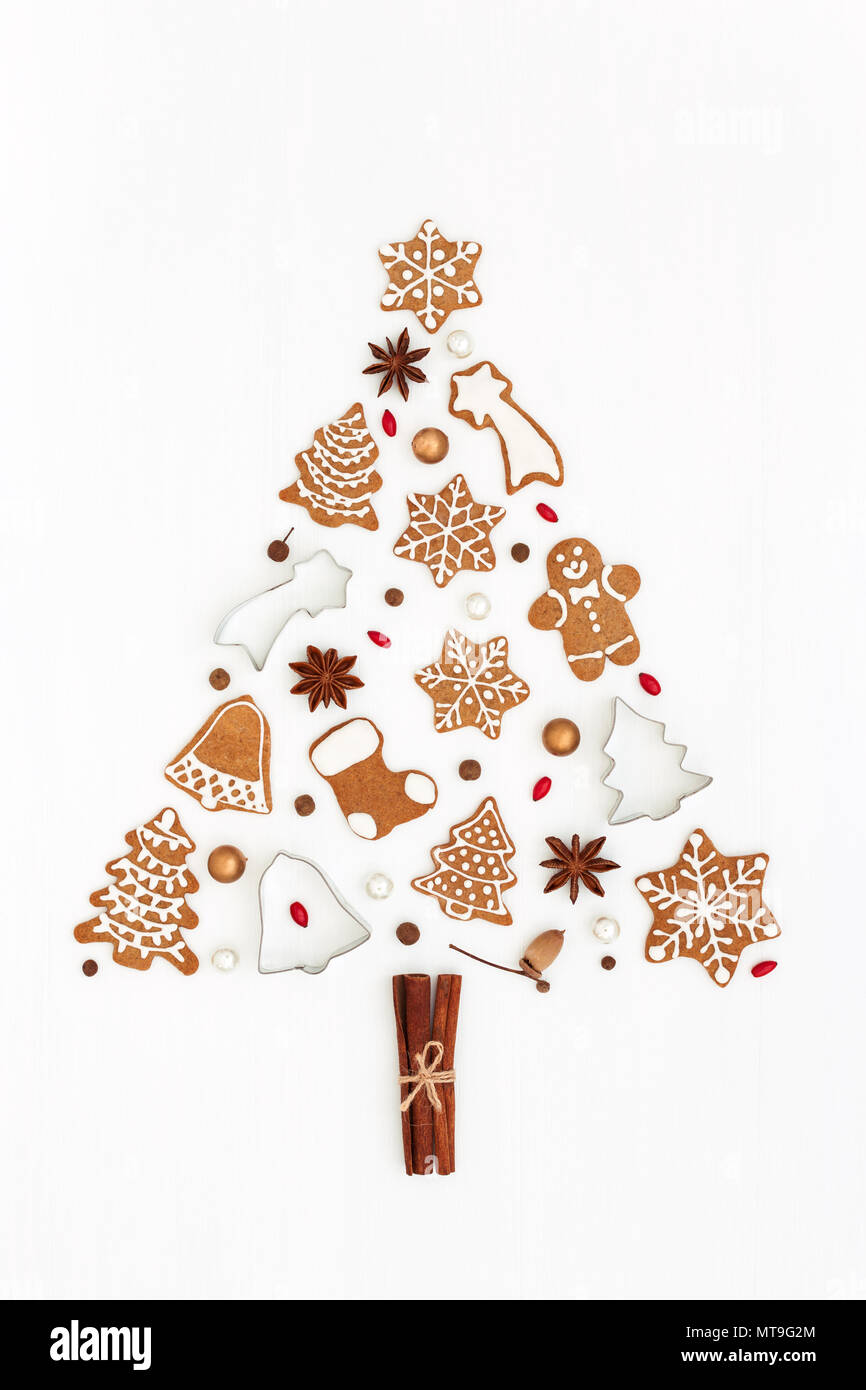 Albero di Natale fatto di gingerbread cookie, stelle anice, gli stampi da forno e perle su sfondo bianco. Natale e Anno Nuovo simbolo. Lay piatto. Foto Stock