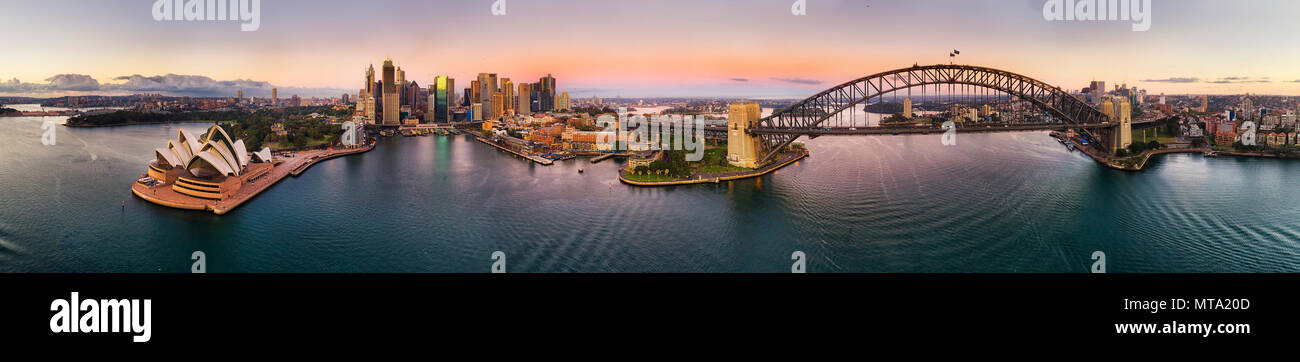 Ultra wide di 270 gradi antenna panorama della città di Sydney CBD i punti di riferimento sulle sponde del porto di Sydney a sunrise sotto il cielo rosa. Foto Stock