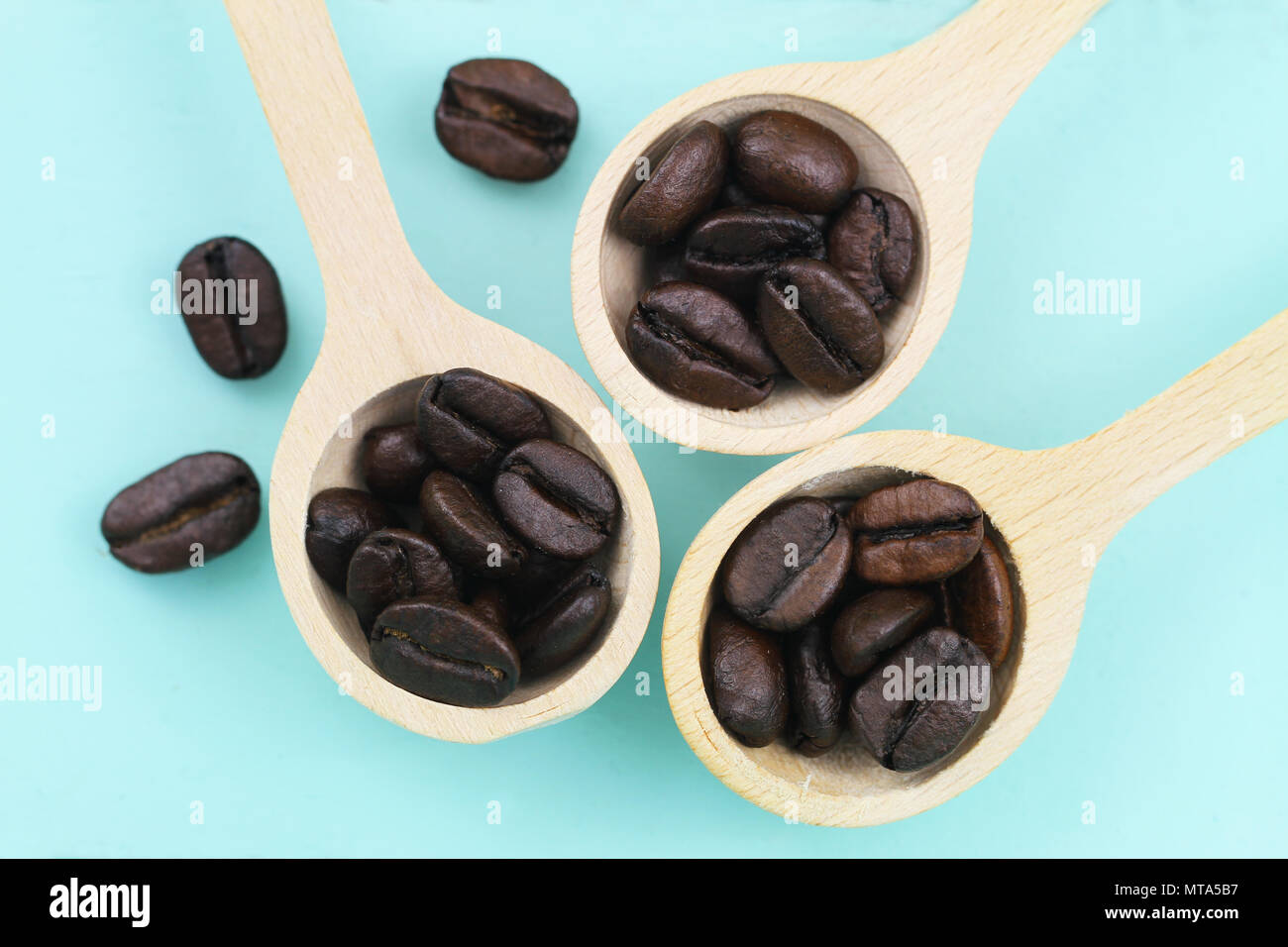 Chicchi di caffè tostati su cucchiai di legno Foto Stock