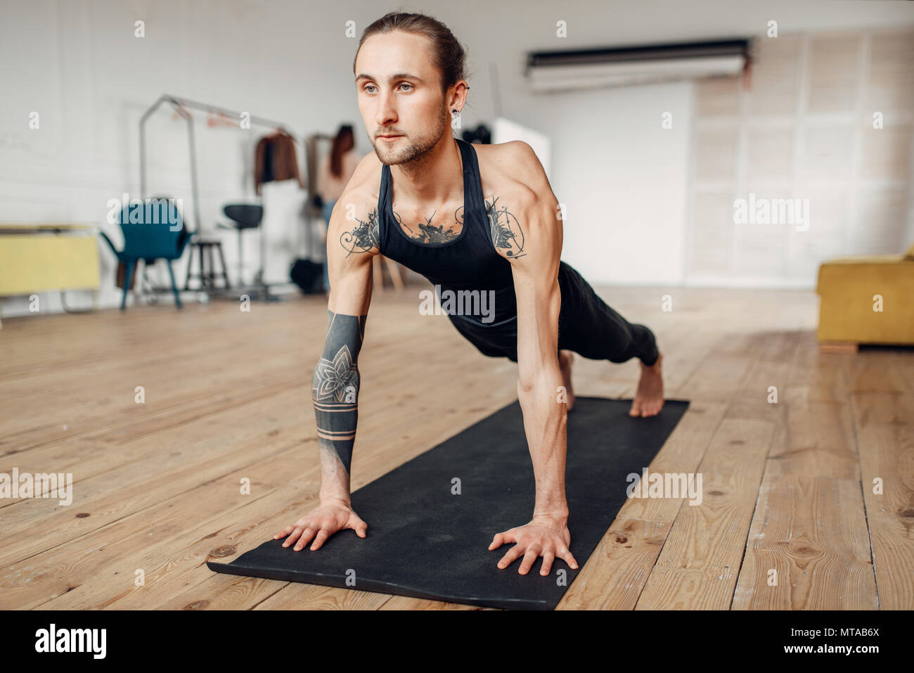 Yoga maschio con tatuaggio sul lato facendo spingere verso l'alto esercizio in palestra con grunge interni. Allenamento fitness in ambienti interni Foto Stock