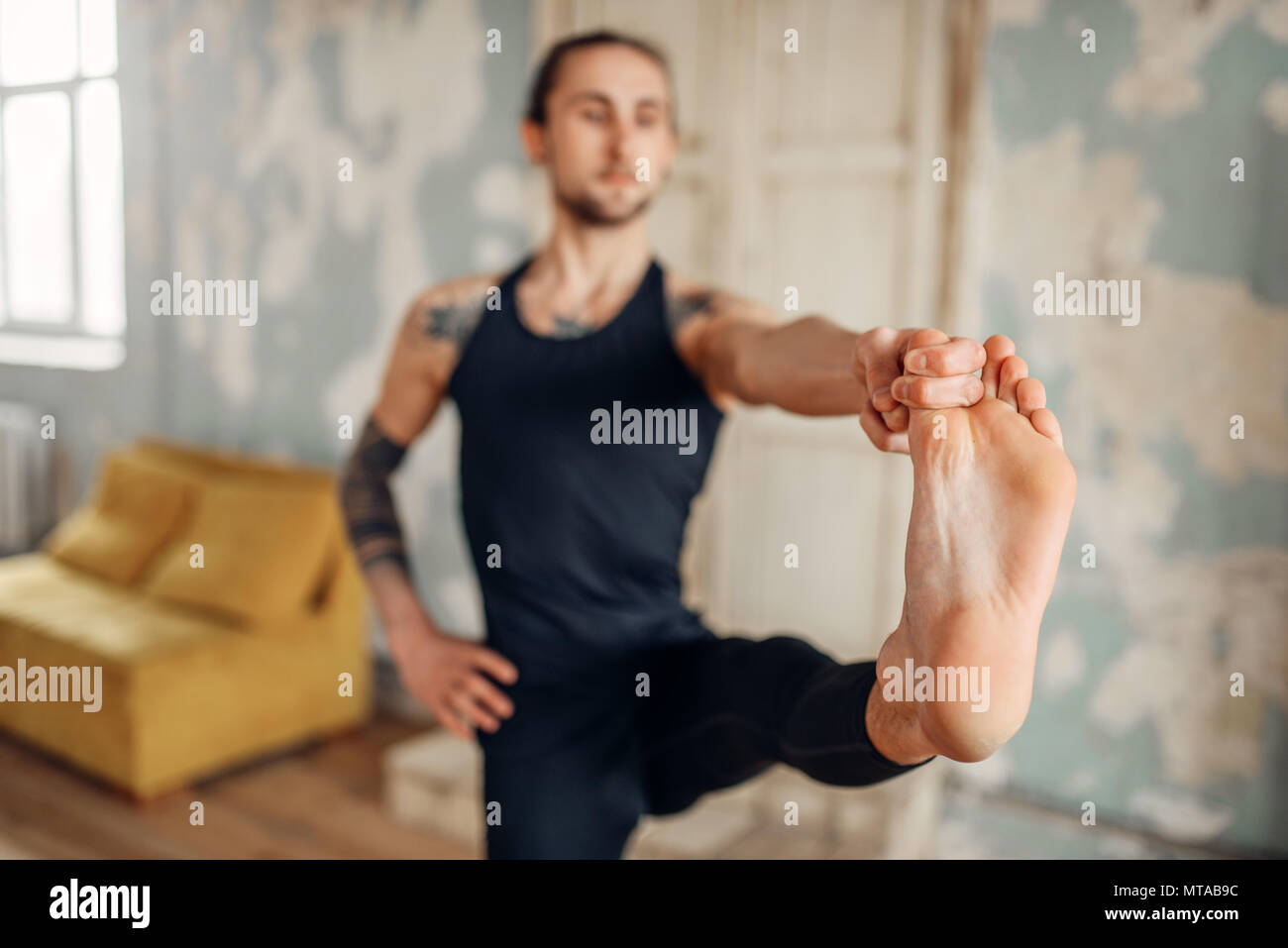 Lo Yoga con tattoo facendo stretching esercizio in palestra con grunge interni. La meditazione di yogi studio Foto Stock