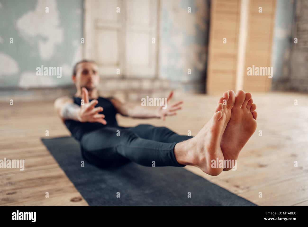 Yoga maschio in classe, premere la formazione. Esercizio sul tappeto in palestra con grunge interni. Montare l'allenamento al chiuso Foto Stock