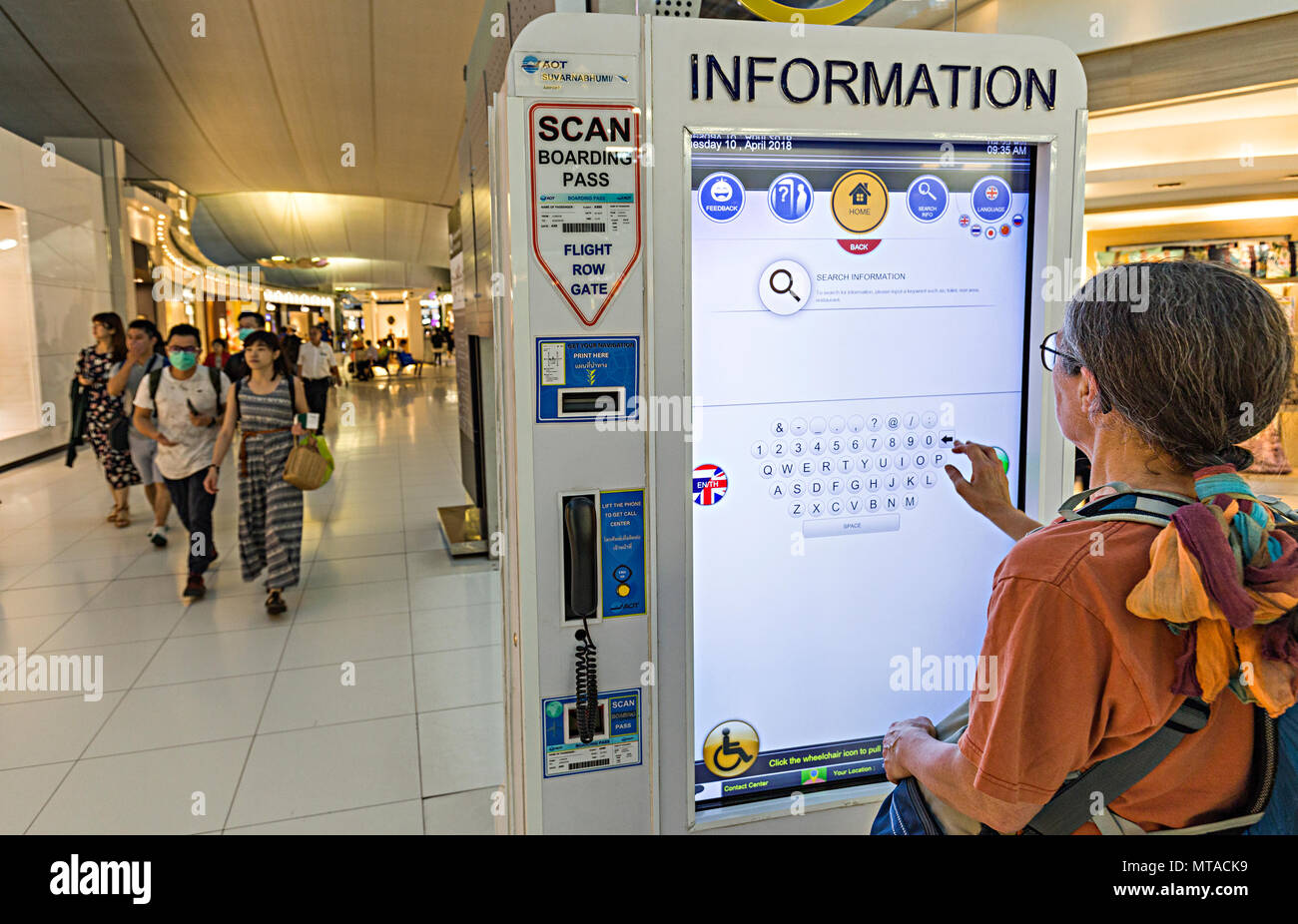 Donna che utilizza interactive information board, concourse all'aeroporto di Bangkok, Tailandia Foto Stock