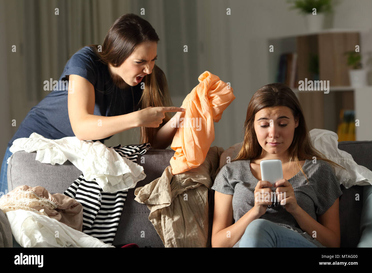 Arrabbiato donna scolding al suo confuso compagno di stanza di seduta su un divano nel salotto di casa Foto Stock