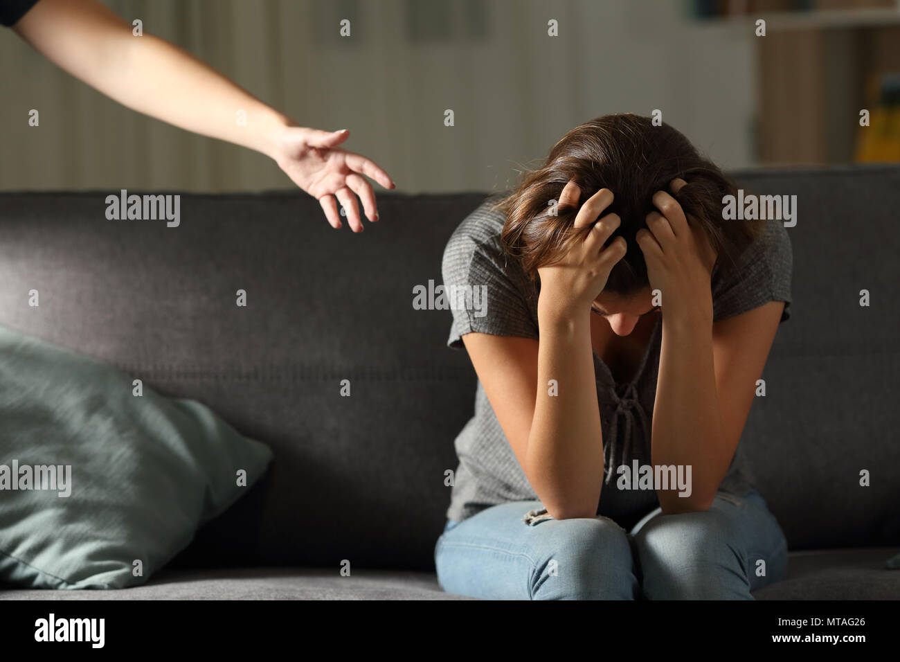 Triste teen e una mano a casa nella notte seduto su un divano nel salotto di casa Foto Stock