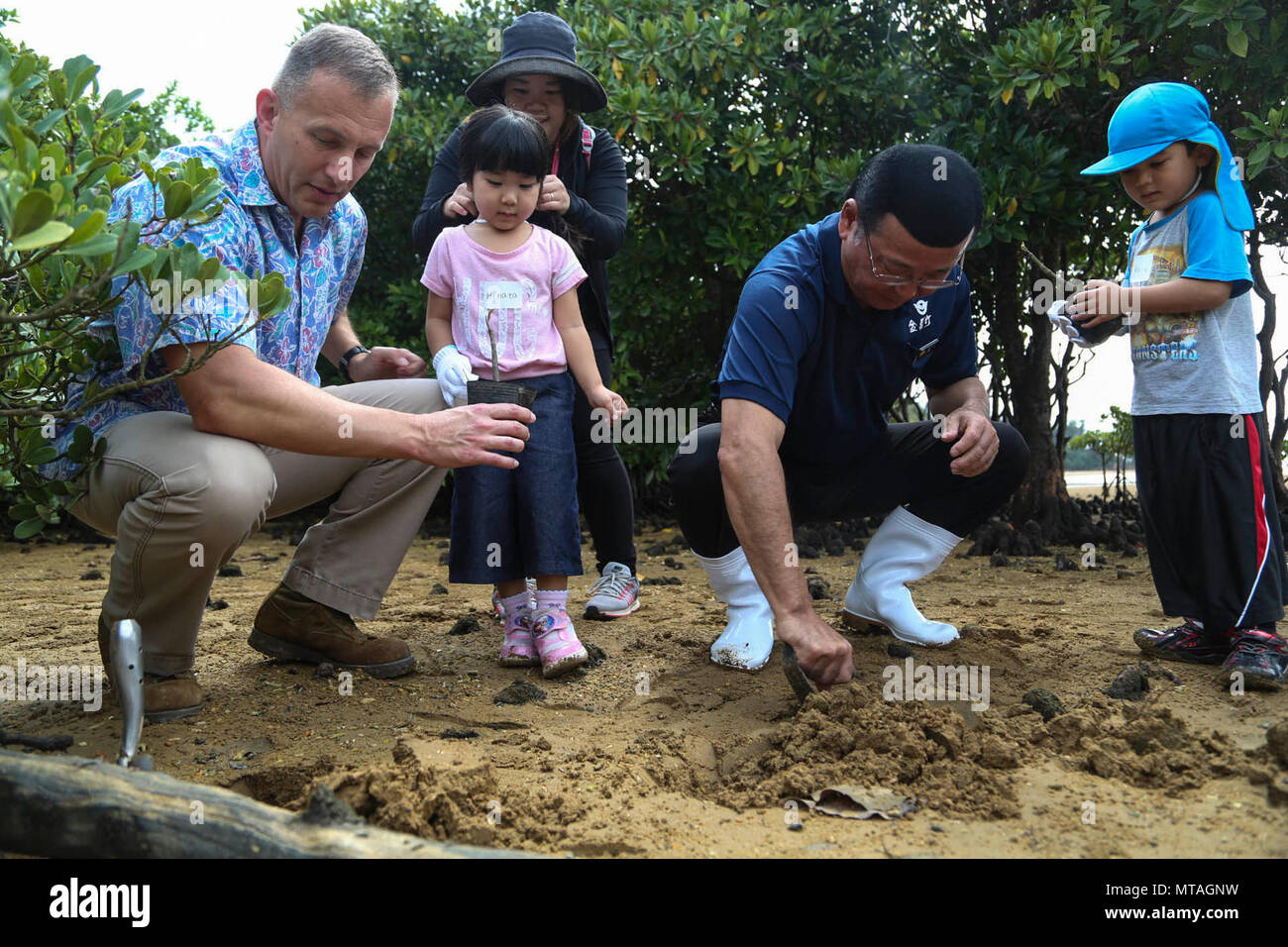 Hajime Nakama, centro a destra, Col. Brian Howlett, sinistra lontana, e residenti di Okinawa pianta un alberello di mangrovie durante un giorno di terra di pulizia e la piantumazione di alberi 21 aprile alla natura Mirai Kan in Kin Town, Okinawa, in Giappone. Circa un centinaio di partecipanti raccolto spazzatura lungo il fiume Okukubi e piantate mangrove alberelli accanto al letto del fiume. Nakame è il sindaco della città di Kin. Howlett è Camp Hansen comandante di Camp e il comandante della terza Marine forza expeditionary Sede Gruppo. Foto Stock