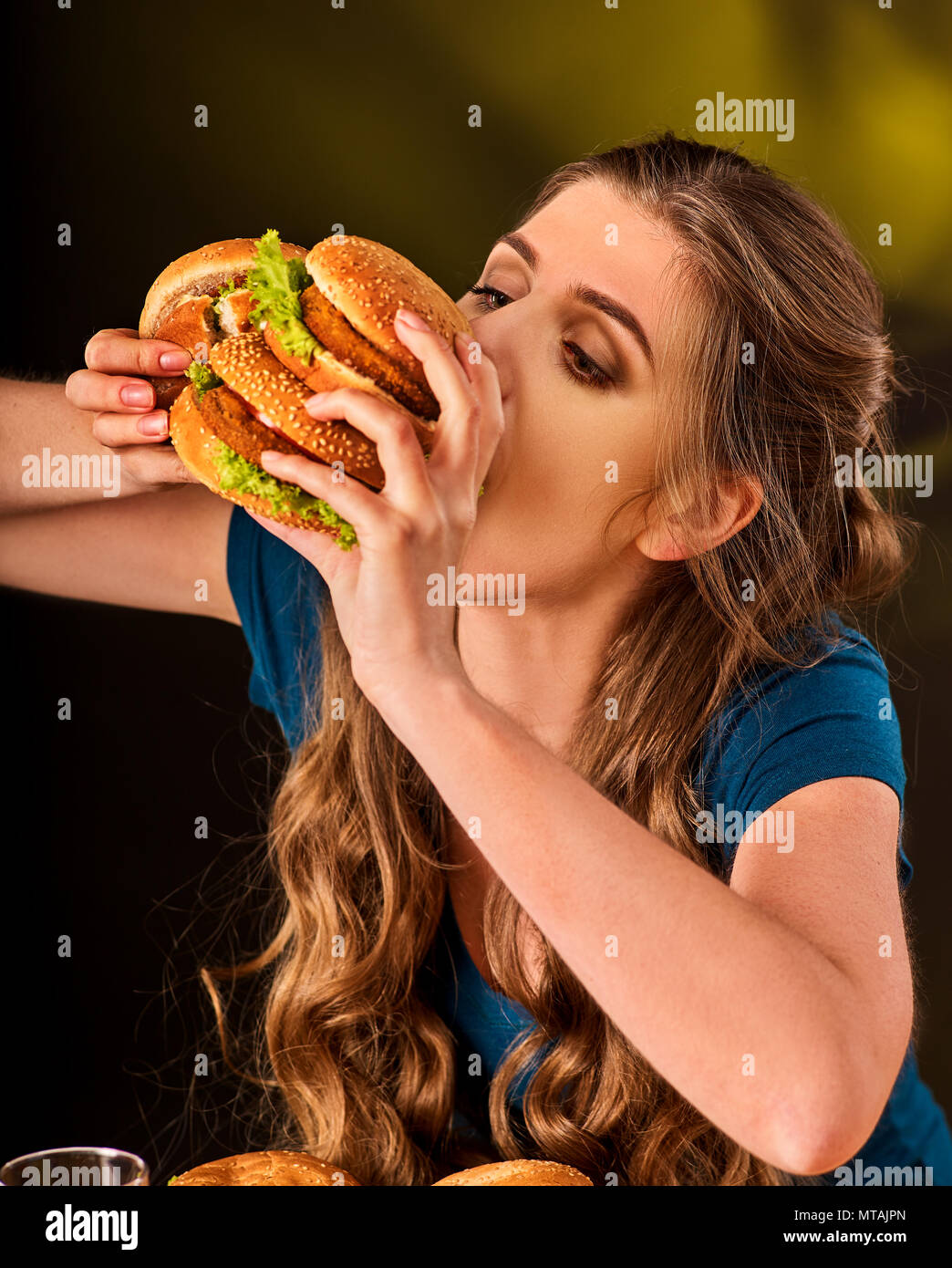 Donna di mangiare patatine e hamburger con la pizza. Foto Stock