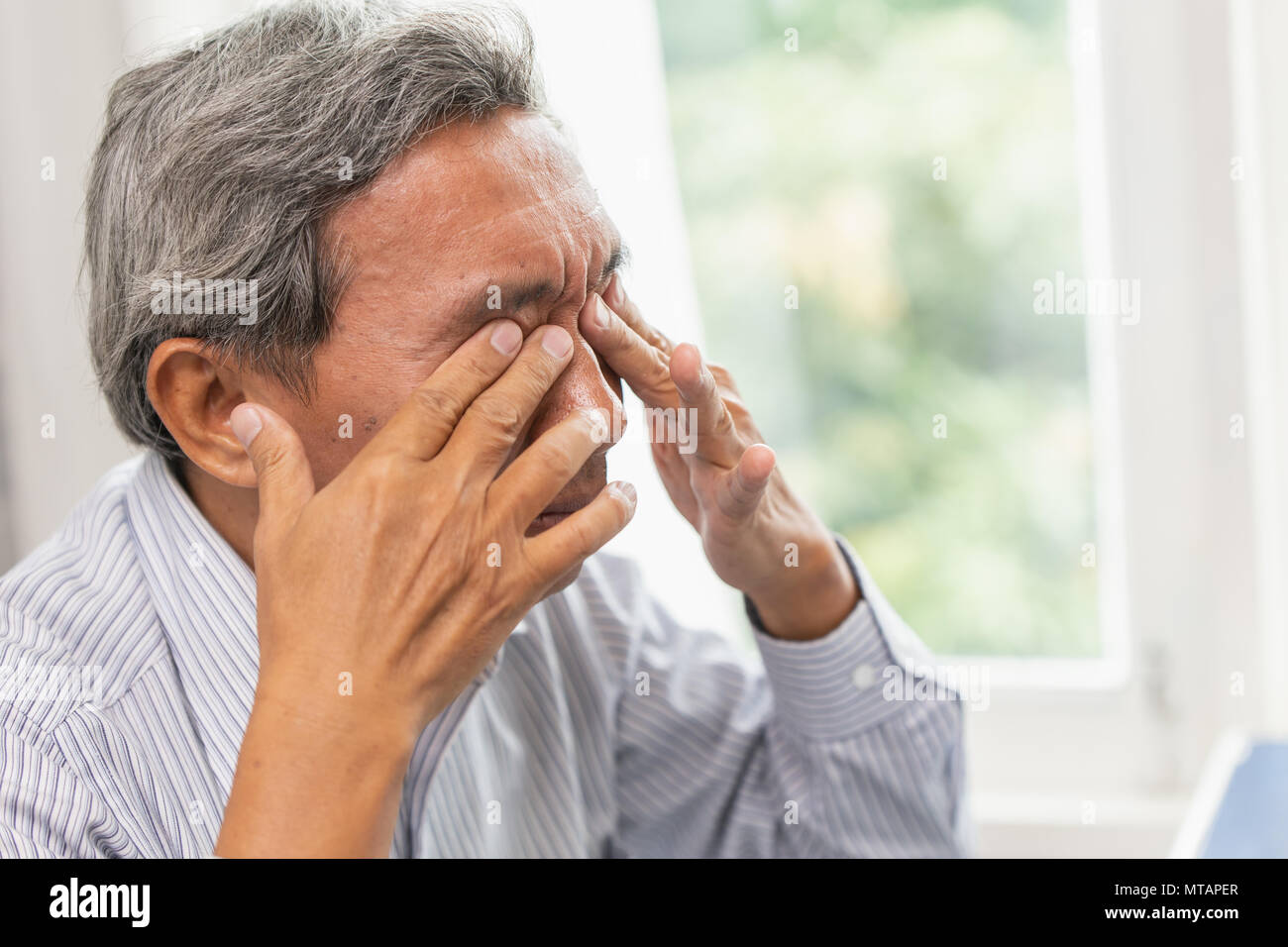 Asian anziani occhio Auto massaggio lenitivo dal problema di irritazione fatica e stanchi dopo una giornata di duro lavoro o computer vision sindrome Foto Stock