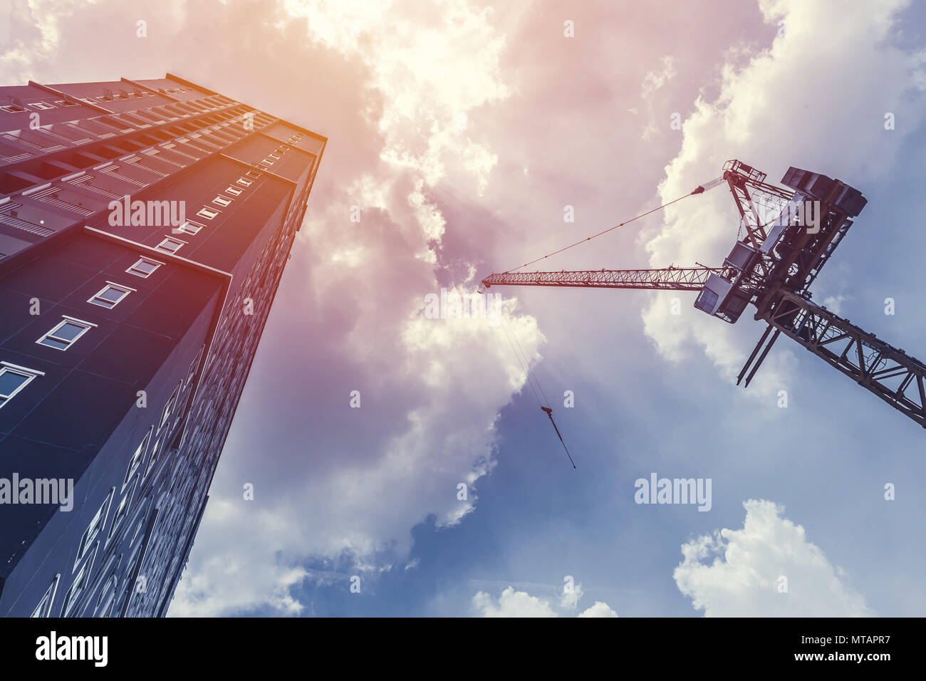 Gru da cantiere e con altezza di costruzione di un condominio contro il cielo blu Foto Stock