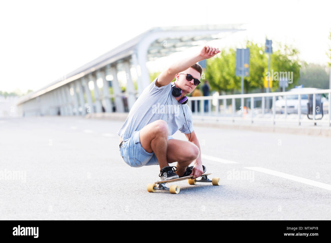 Guidatore di skateboard in occhiali da sole longboard corse su strada  asfaltata in città, posizione bassa trucco ride Foto stock - Alamy