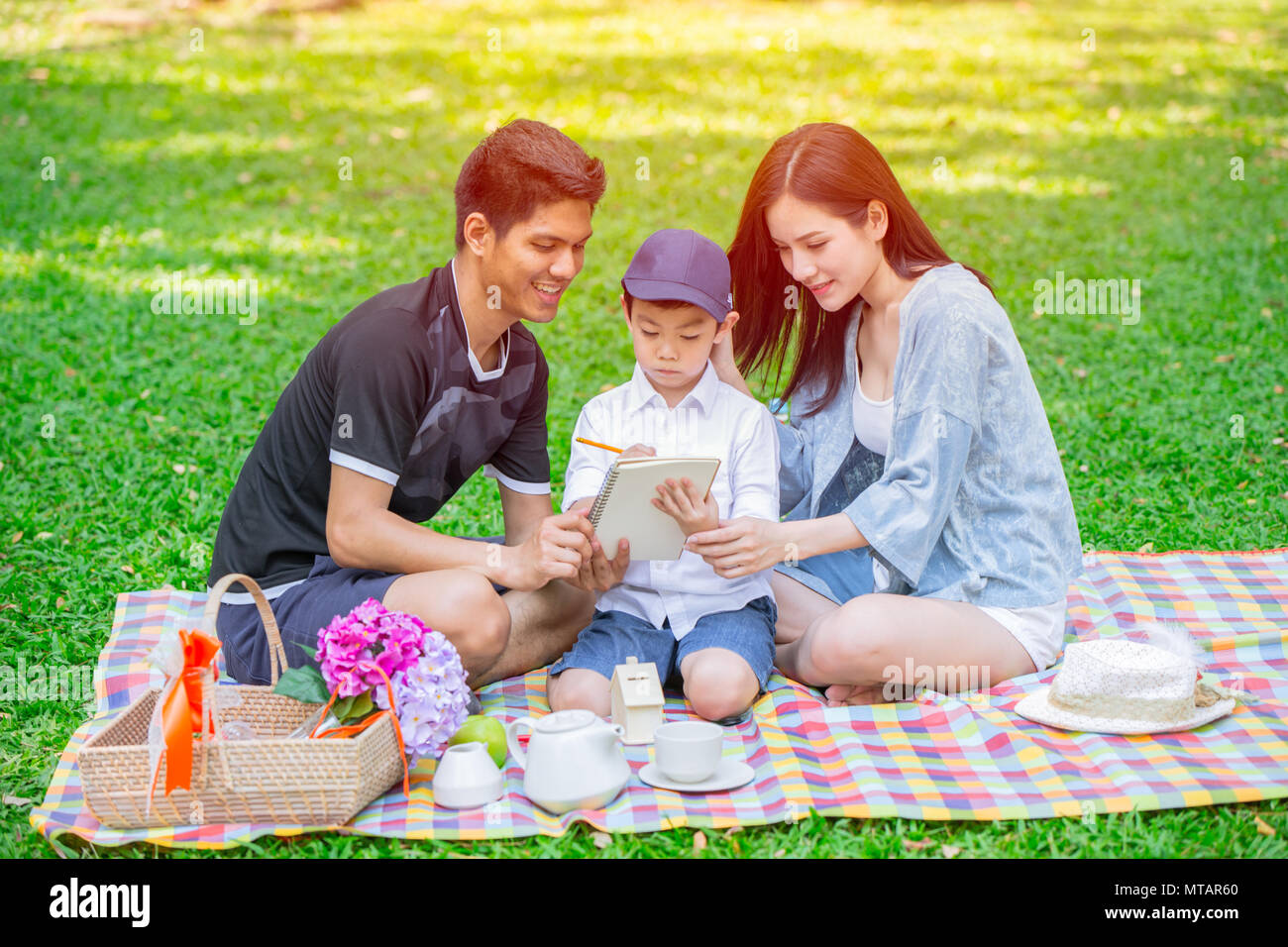 Asian teen teching famiglia istruzione al capretto felice vacanza momento picnic nel parco verde Foto Stock