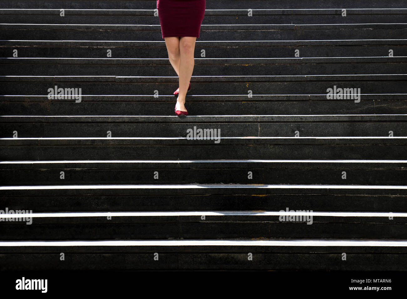 Le gambe di una giovane donna in rosso le scarpe e abiti avvicinando mentre camminando per la città di scale pubbliche Foto Stock