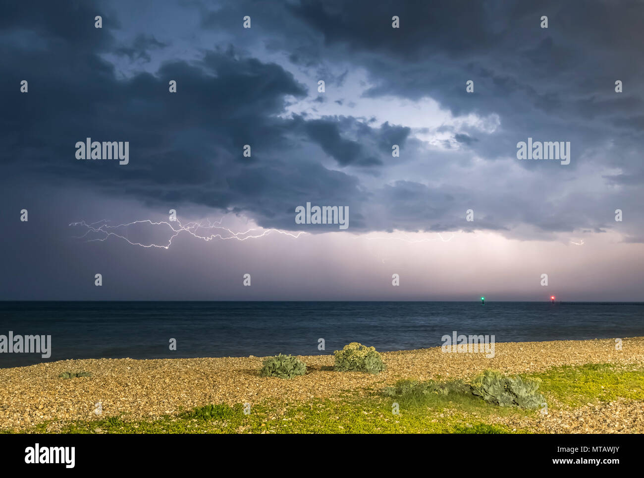 Colpo di fulmine sul mare di notte, con dark moody nuvole temporalesche, oltre la British south coast in Inghilterra, Regno Unito. Foto Stock