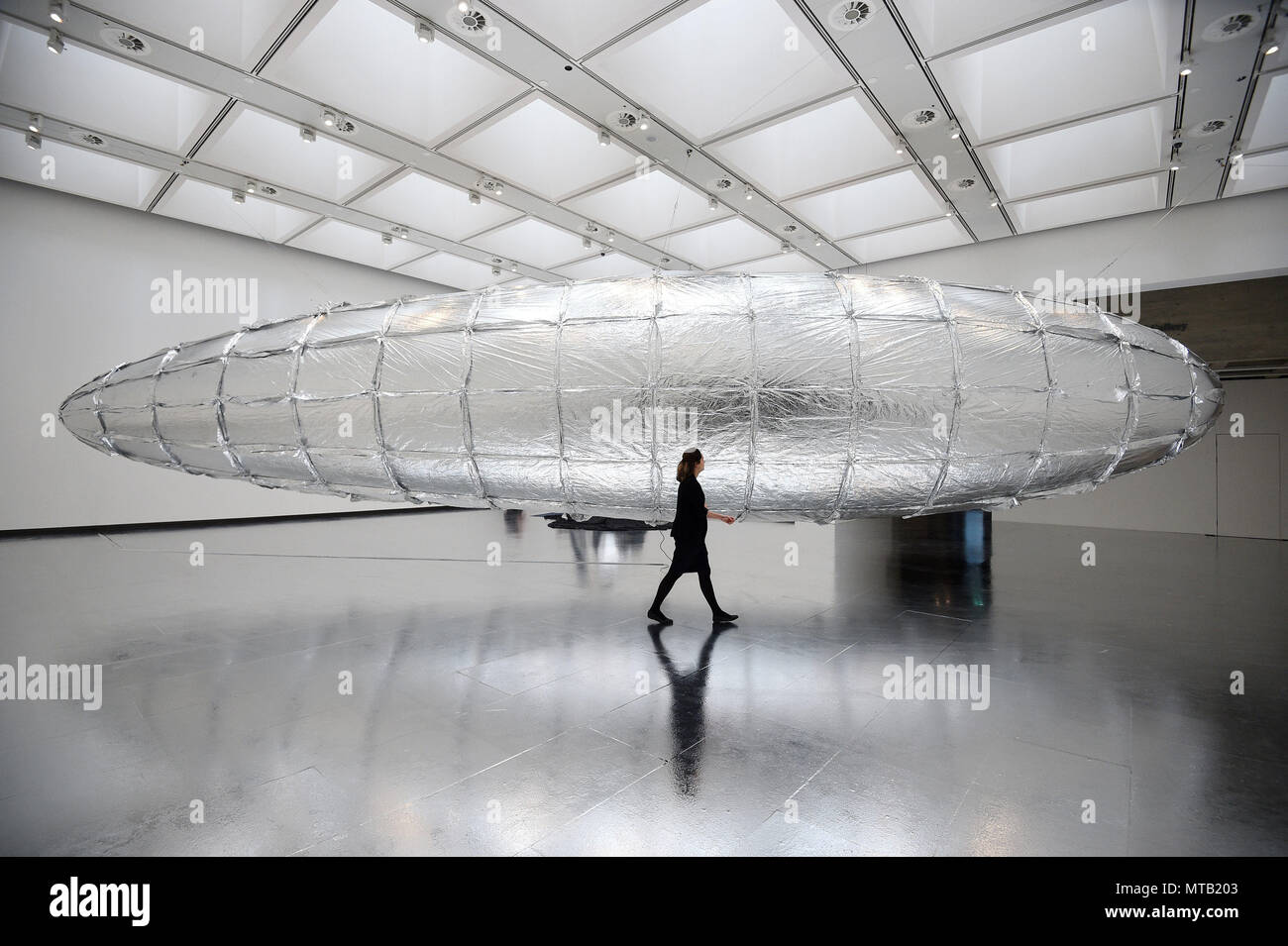 Un assistente di galleria guarda disposti ad essere vulnerabili - palloncino metallizzato durante un photocall per Lee Bul: Crash, una nuova mostra presso la Hayward Gallery di Londra centrale. Foto Stock