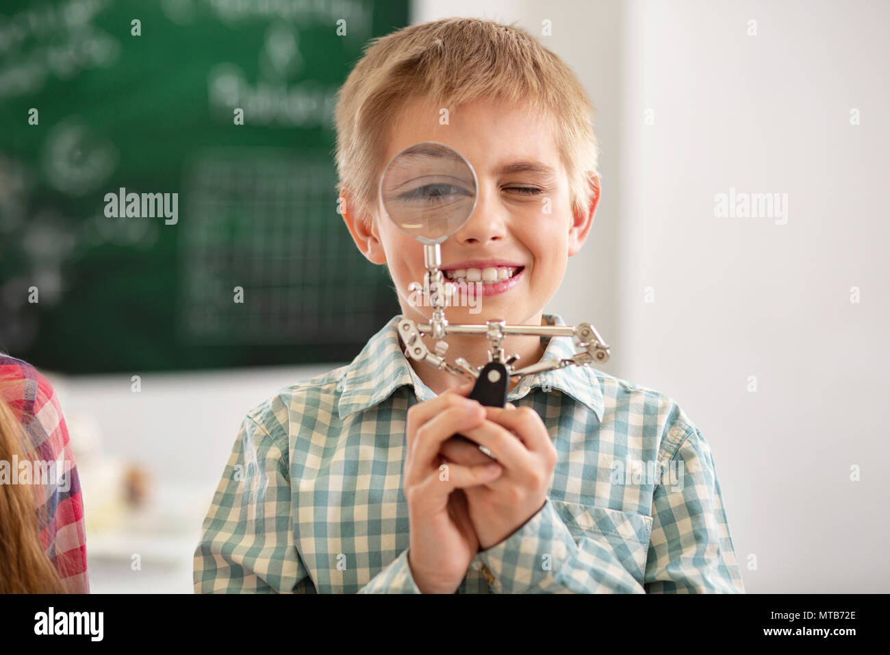 Allegro bel ragazzo che guarda nella lente di ingrandimento Foto Stock