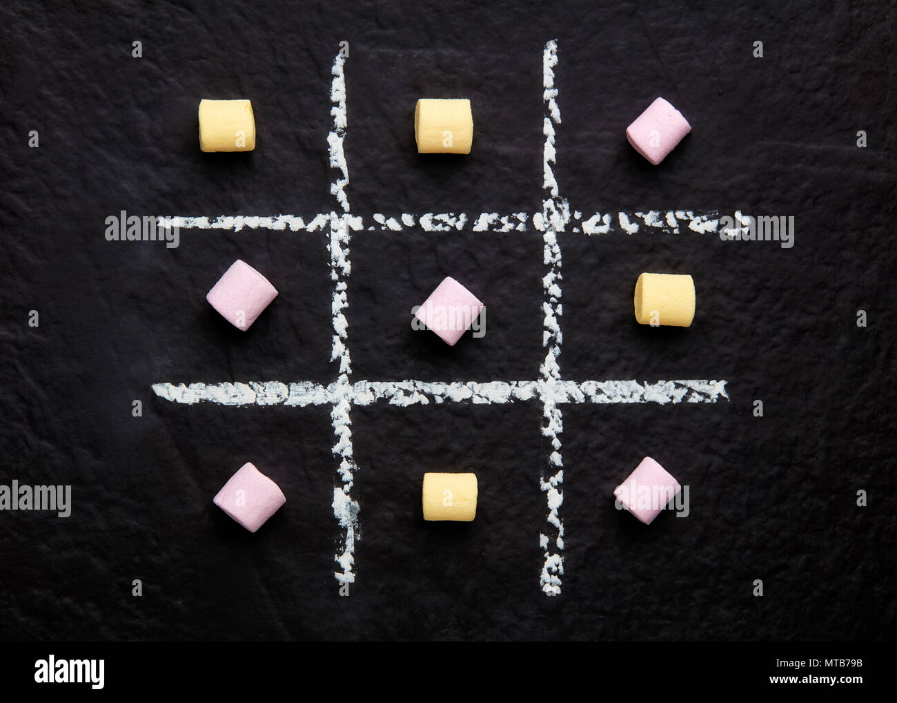 Tic Tac Toe xo gioco con colorati marshmallows sulla trama della superficie nera Foto Stock