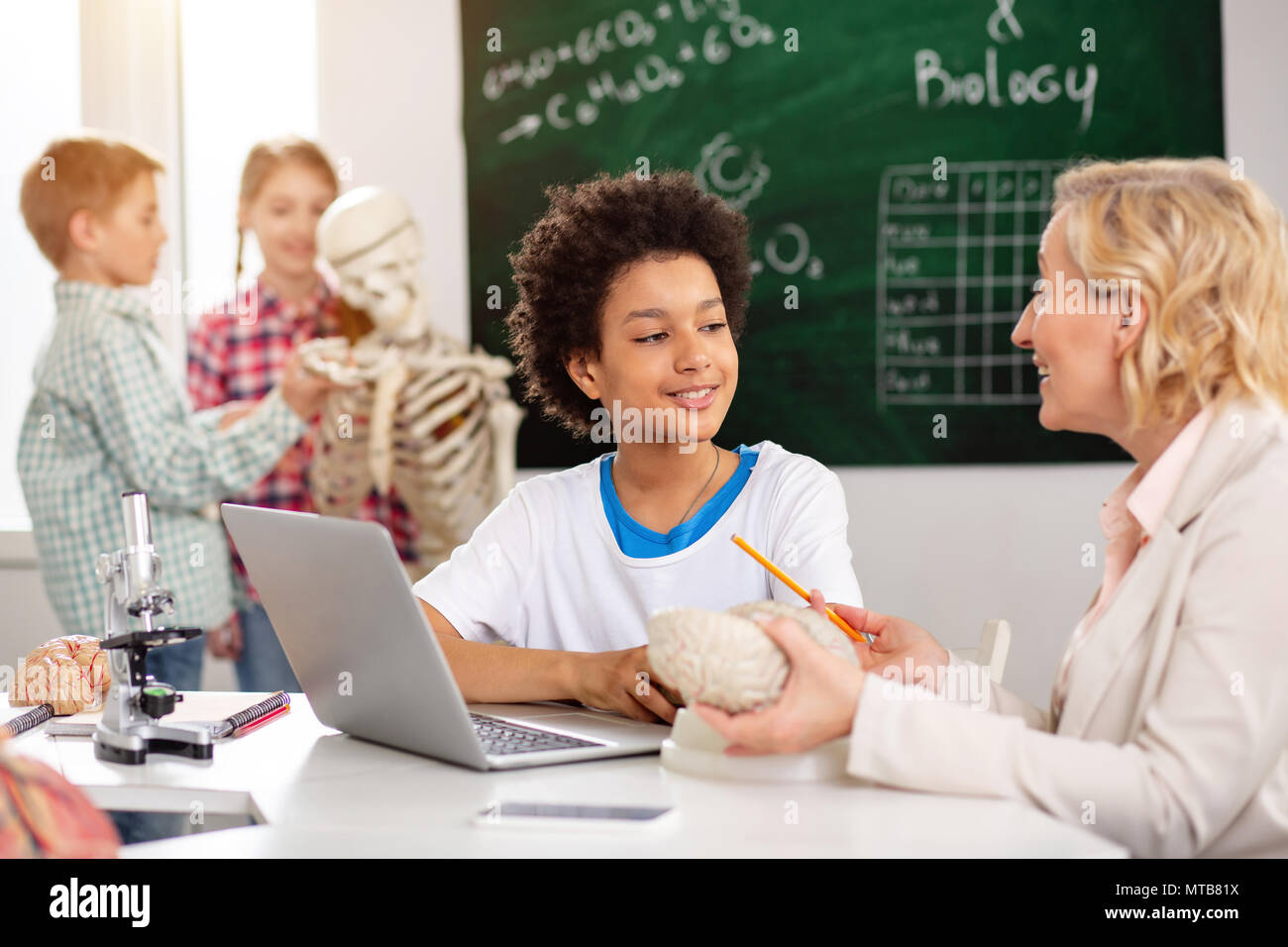 Gioioso positivo ragazzo seduto davanti al computer Foto Stock