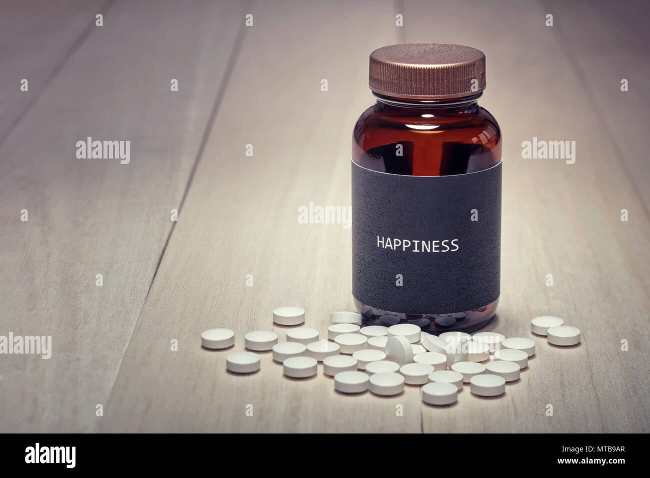 Concetto di anti-depressive il consumo di stupefacenti e la felicità. Un contenitore di farmaco con etichetta nera felicità scritto su di esso. Pillola bianco compresse nella parte anteriore. Camera fo Foto Stock