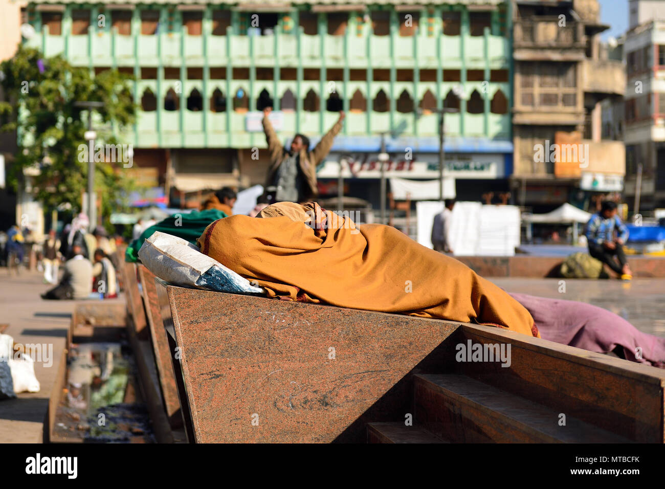 Il povero contadino indiano dorme su una scultura in acciaio nel centro città avvolto in una coperta nella città di Ahmedabad in Gujarat in India Foto Stock