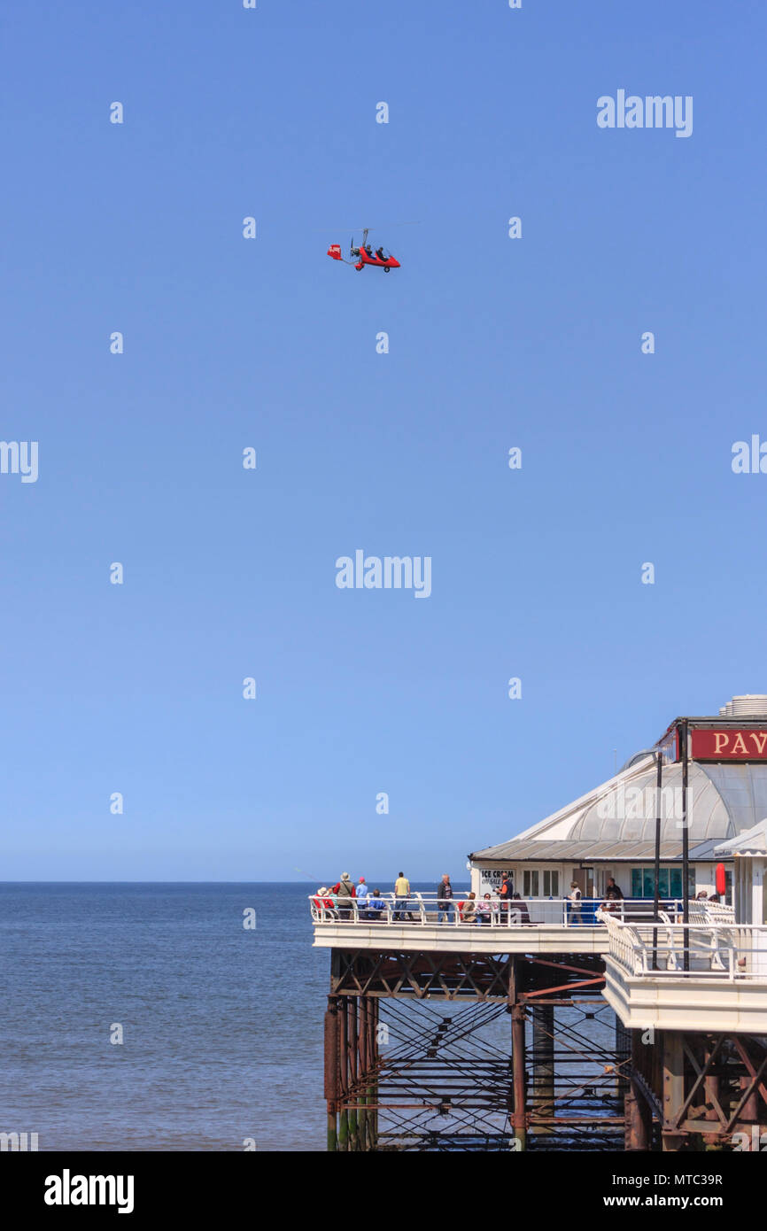Un ultraleggero rosso sorvolano Cromer Pier. Persone di pesca e godersi il sole primaverile a Cromer Pier e Cromer NORFOLK REGNO UNITO Foto Stock