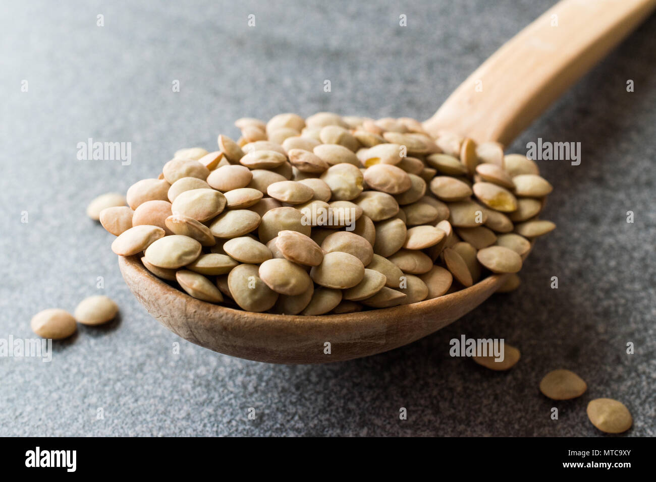 Materie lenticchie in cucchiaio di legno. Prodotto organico. Foto Stock