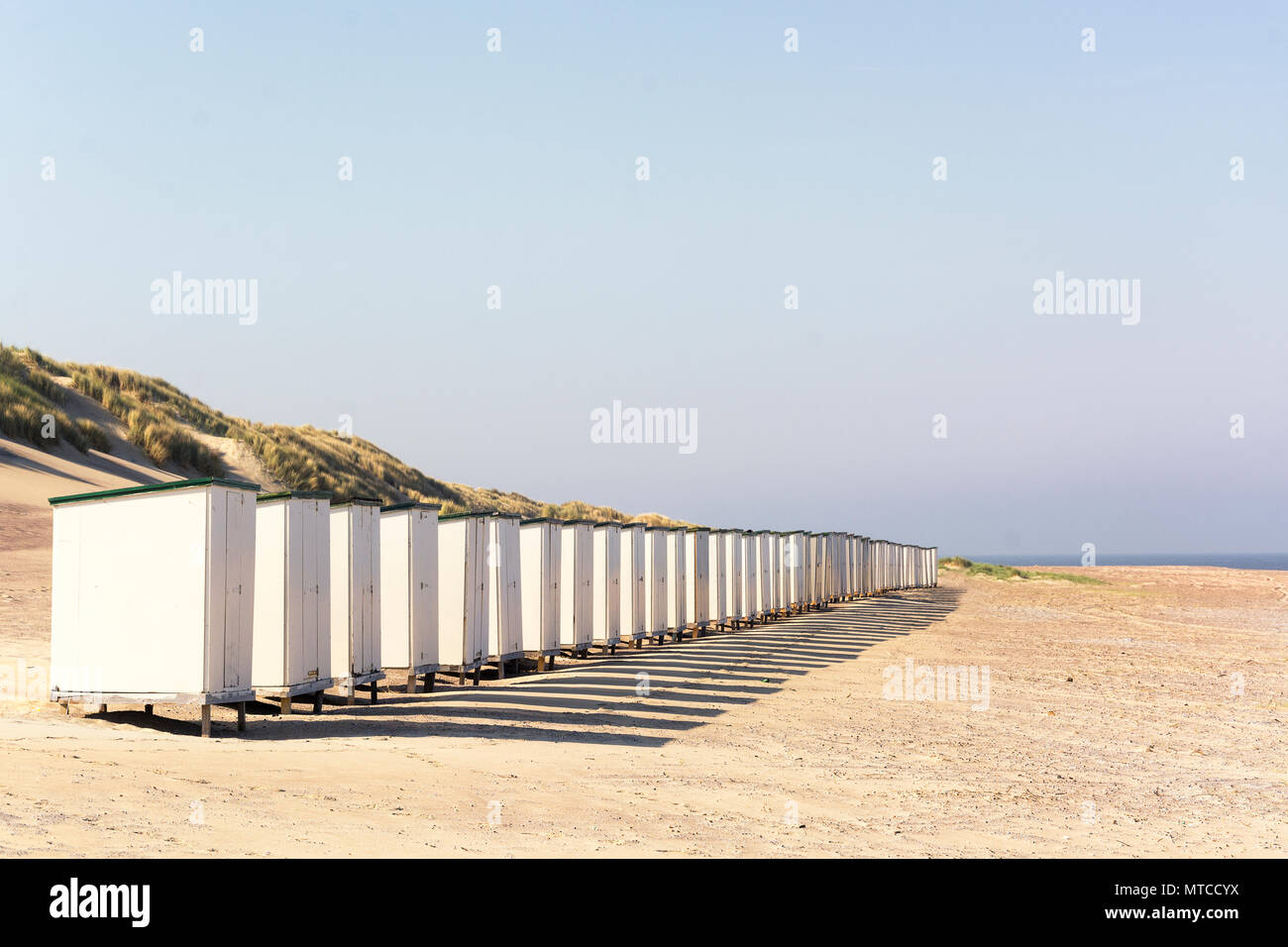 Fila di spiaggia bianca di capanne su un vuoto di sunny beach nella provincia di Zelanda, Paesi Bassi Foto Stock