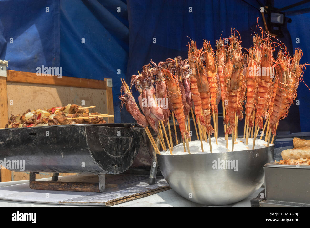 La tabella al kiosk presso Asian Street Food Festival. La strada attuale con offerta di pasto asiatici, grill con Kebab e ciotola con frutti di mare, seppia e lobste Foto Stock