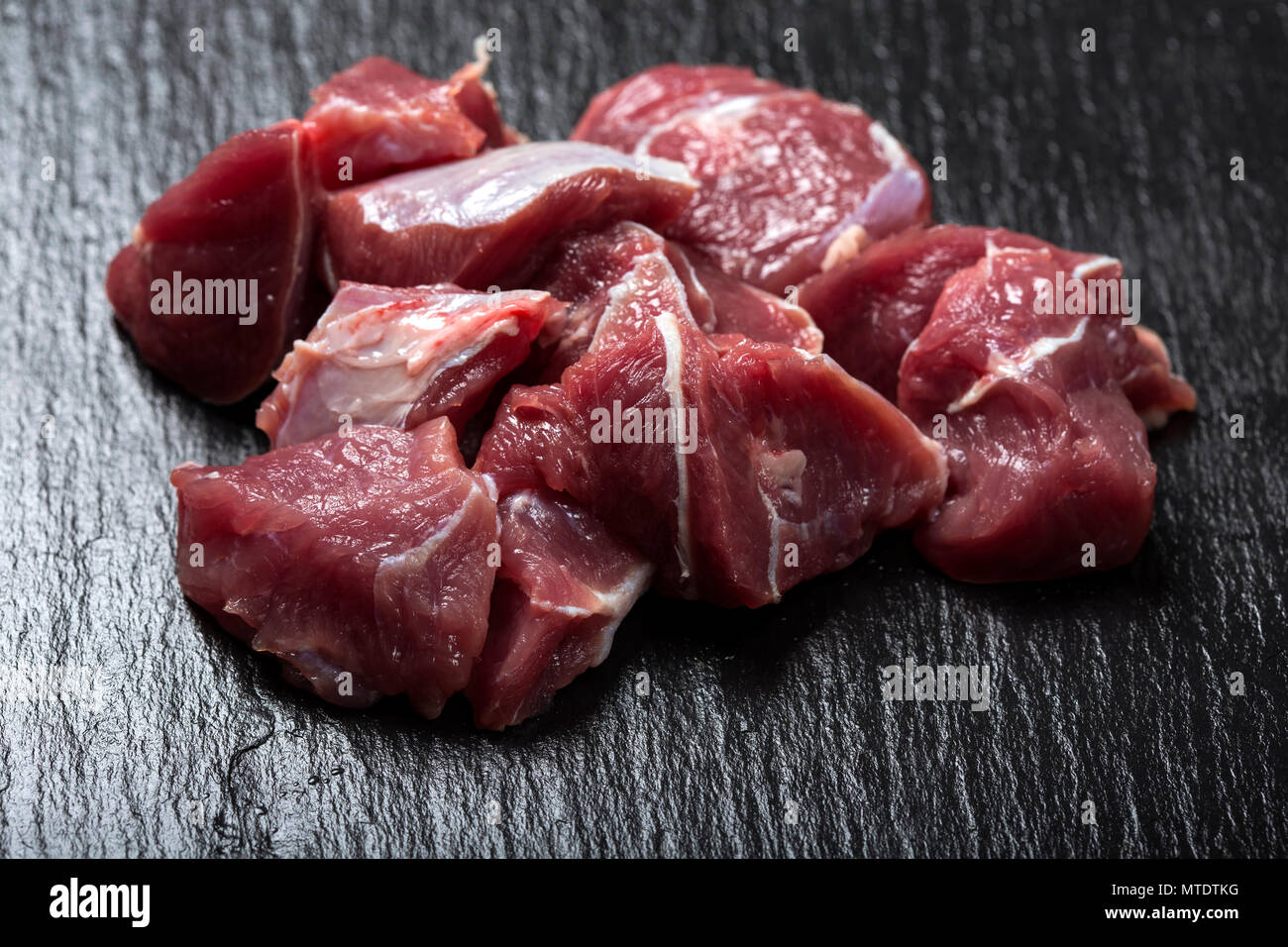 Pezzi di materie di carni bovine al buio su un ardesia - Vista da vicino Foto Stock