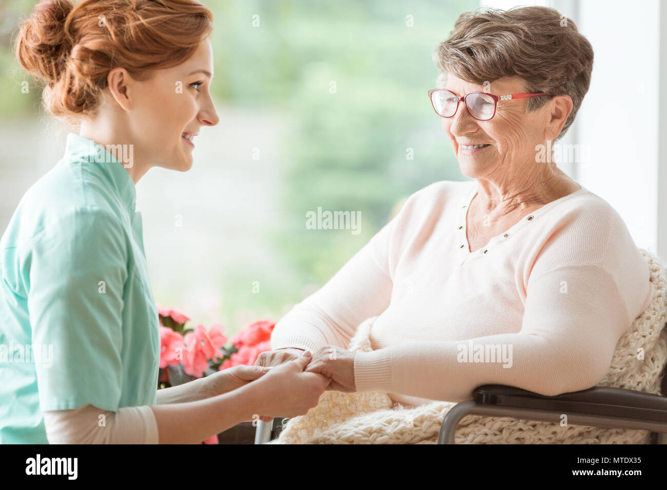 Infermiera compassionevole spiegare un handicap geriatrico paziente con demenza procedure mediche tenendo le mani. Assisted Living house per la penna Foto Stock