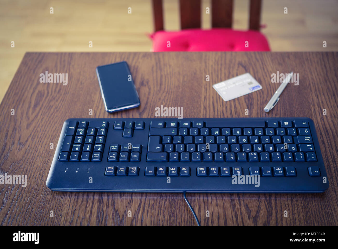Tastiera PC, telefono cellulare, carta di credito e con la penna sul tavolo di legno, viola cast immagine a colori Foto Stock