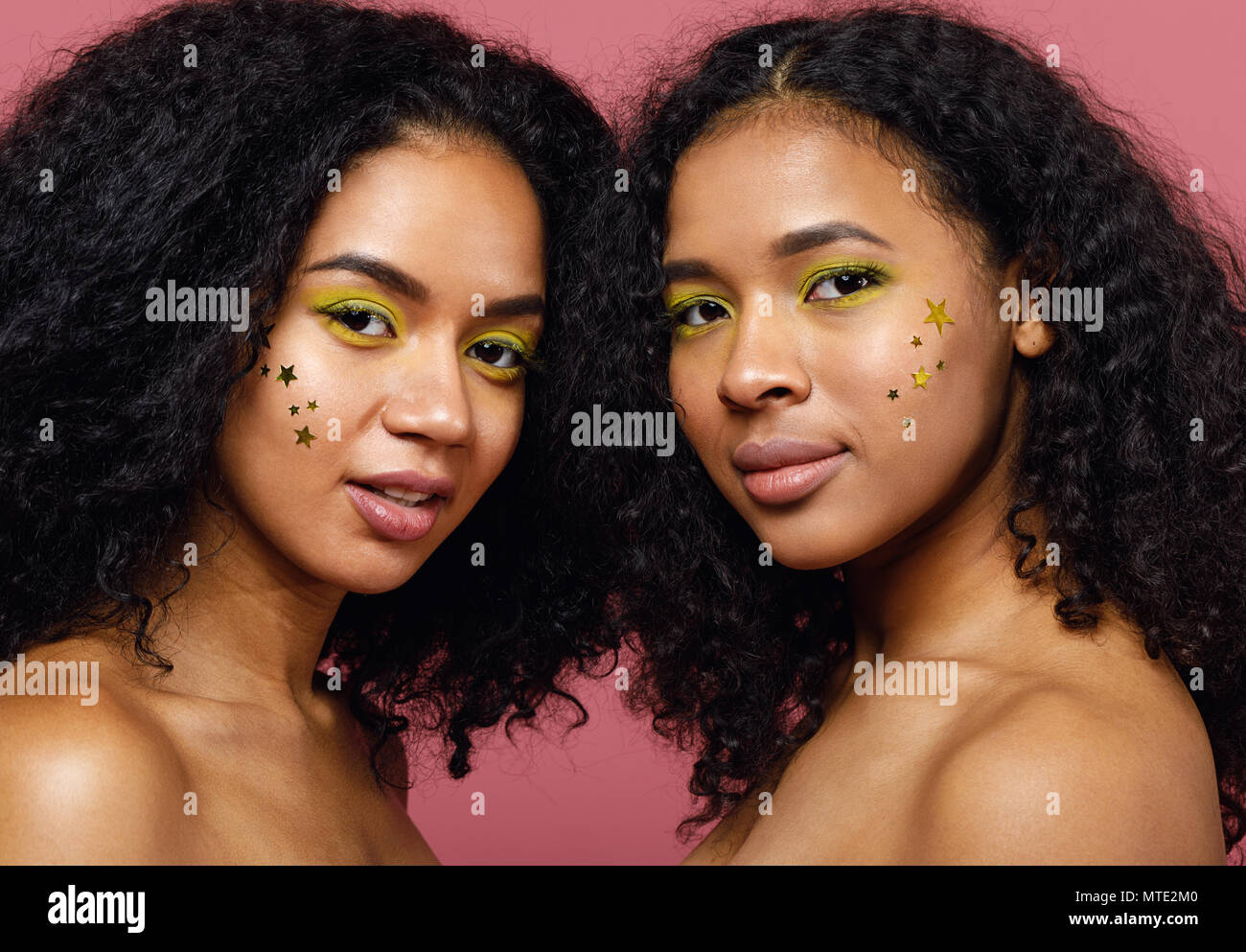 Due giovani donne con la moda costituiscono assieme in studio su sfondo rosa Foto Stock