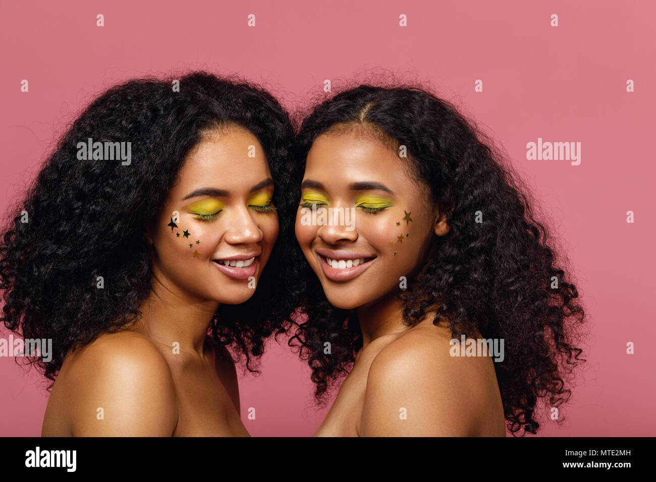 Due donne sorridente con il trucco di moda in piedi su sfondo rosa Foto Stock