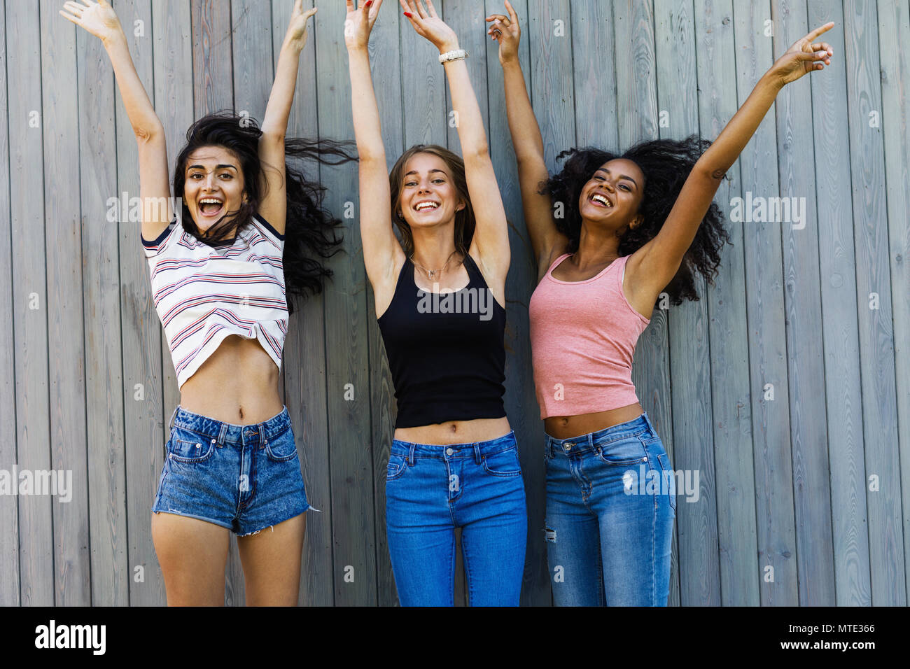 Multirazziale gruppo di amici di sesso femminile avente fun, salto con mani di sollevamento Foto Stock