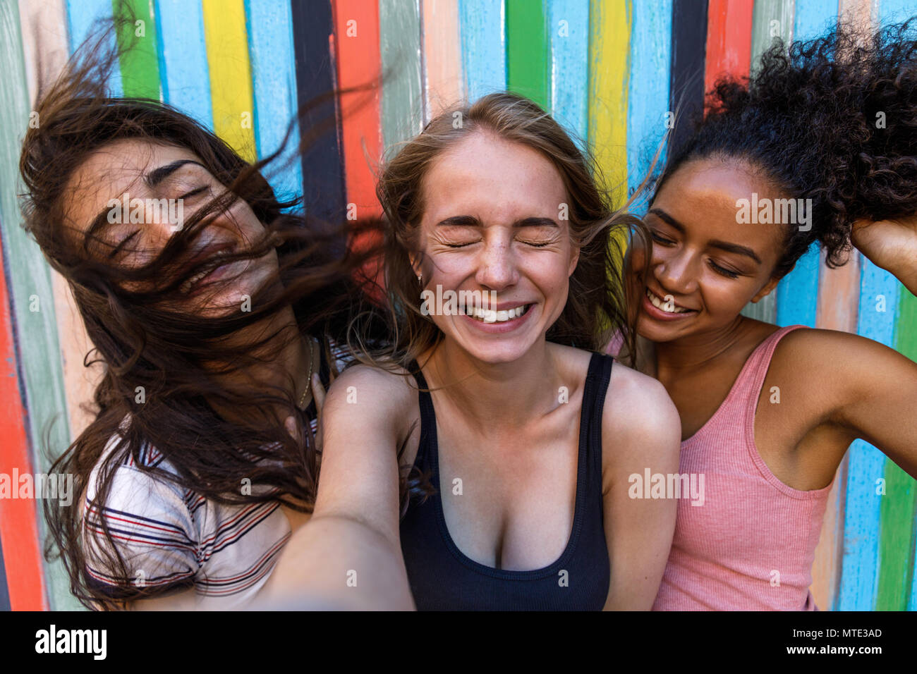 Giovani donne tenendo selfie all'aperto mentre il vento che soffia capelli Foto Stock