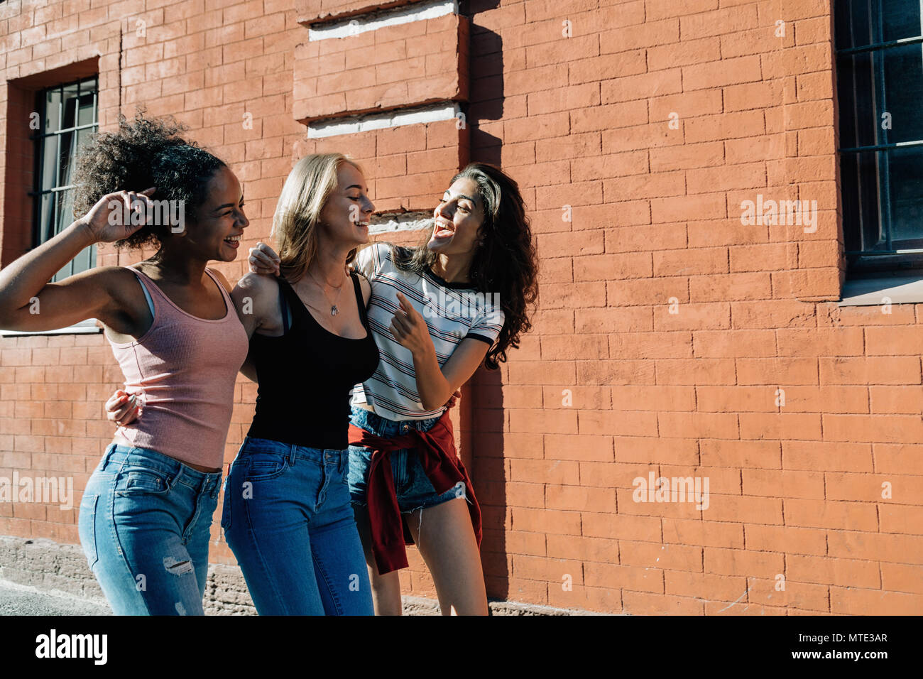 Tre amici felici passeggiate all'aperto, vista laterale Foto Stock