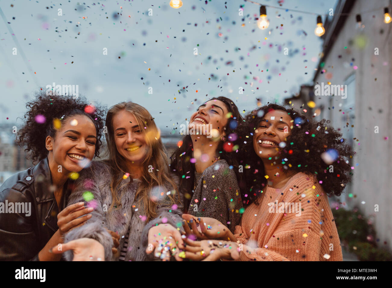 Quattro belle donne sta in piedi in una terrazza sotto coriandoli. Foto Stock