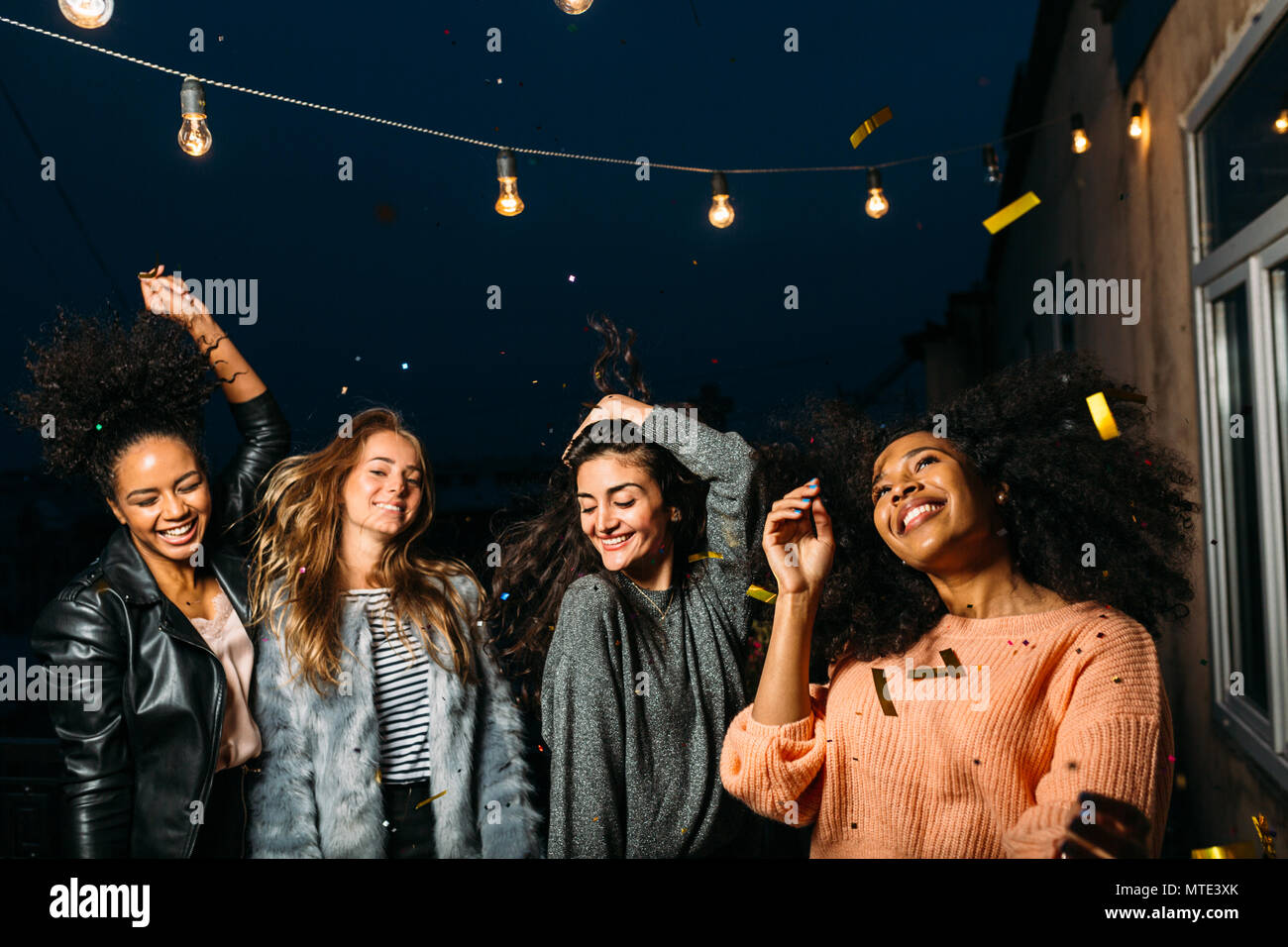 Quattro bellissime donne che danzano su una terrazza di notte Foto Stock