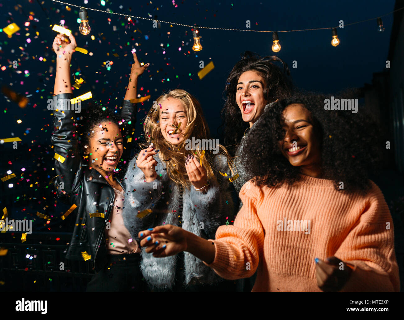 Colpo all'aperto del gruppo amici ridendo sotto i confetti Foto Stock