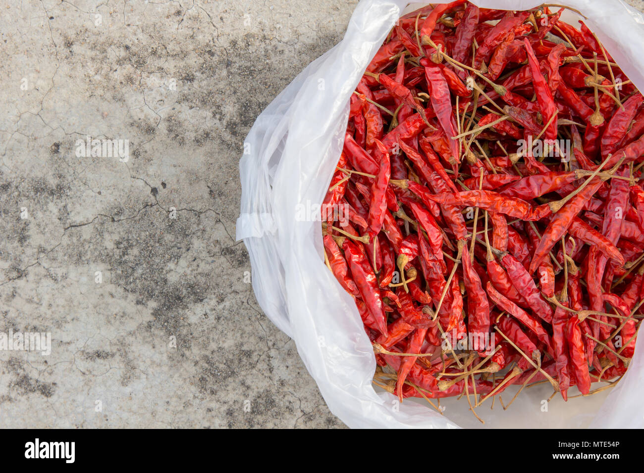 Peperoncini essiccati in bianco di sacchetti di plastica posti sul pavimento in calcestruzzo Foto Stock