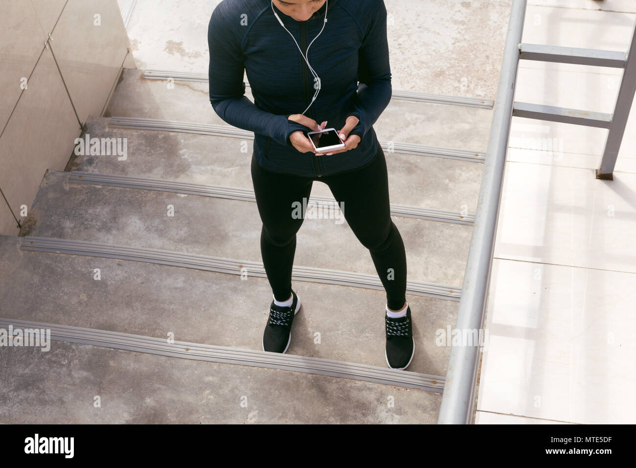 Ritagliato shot di sport donna texting messaggio sul suo dispositivo elettronico Foto Stock