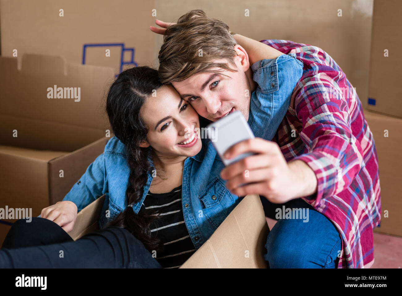 Felice giovane uomo e donna fare un selfie dopo lo spostamento in insieme Foto Stock