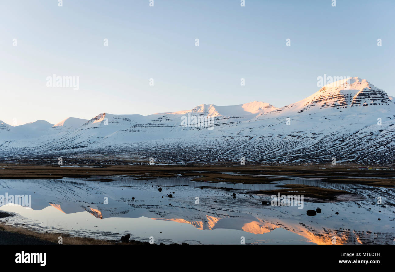 La riflessione di acqua, montagne innevate in un fiordo, Est Islanda Islanda Foto Stock