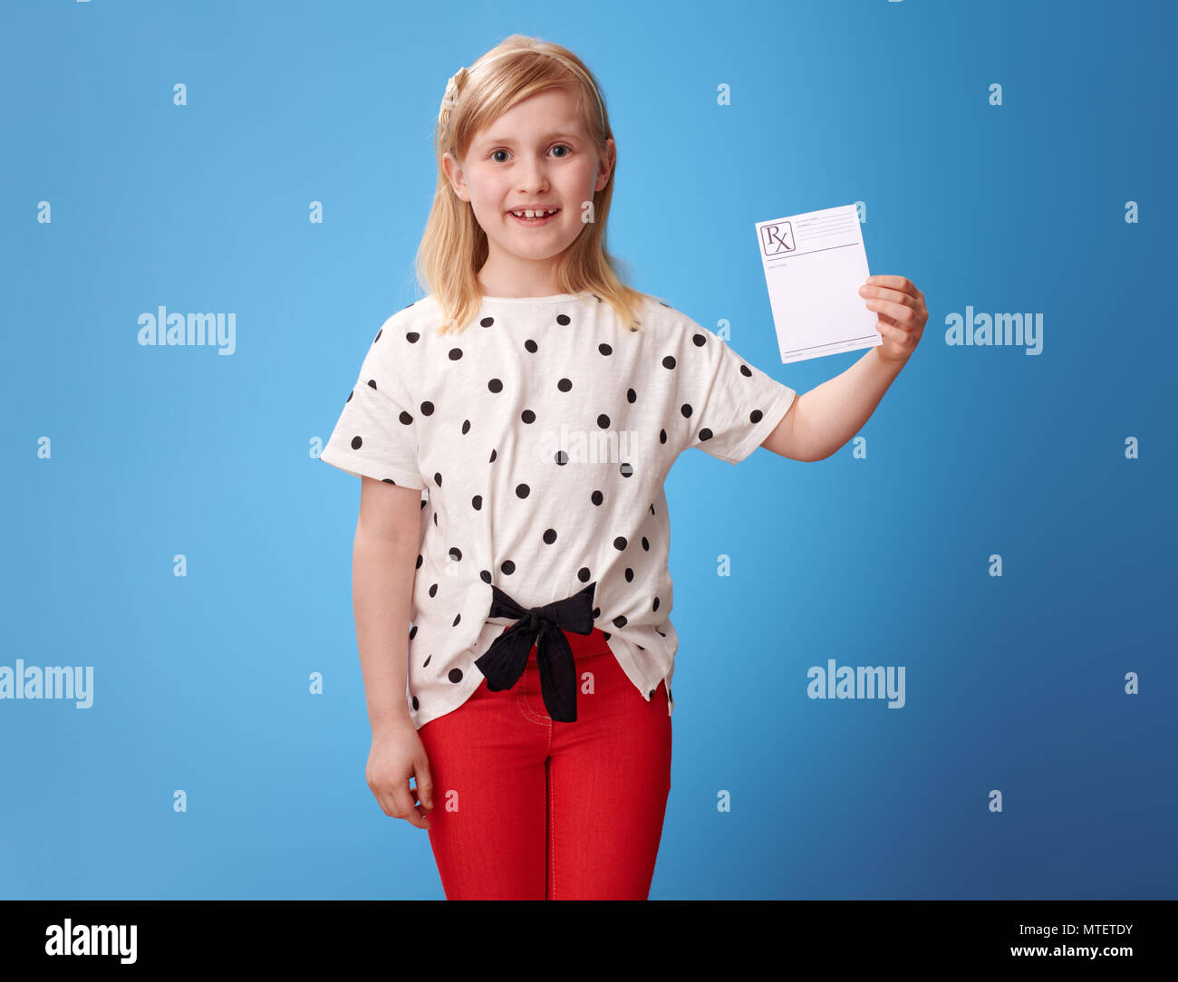 Bambino moderno in pantaloni rossi che mostra la prescrizione isolato su sfondo blu Foto Stock