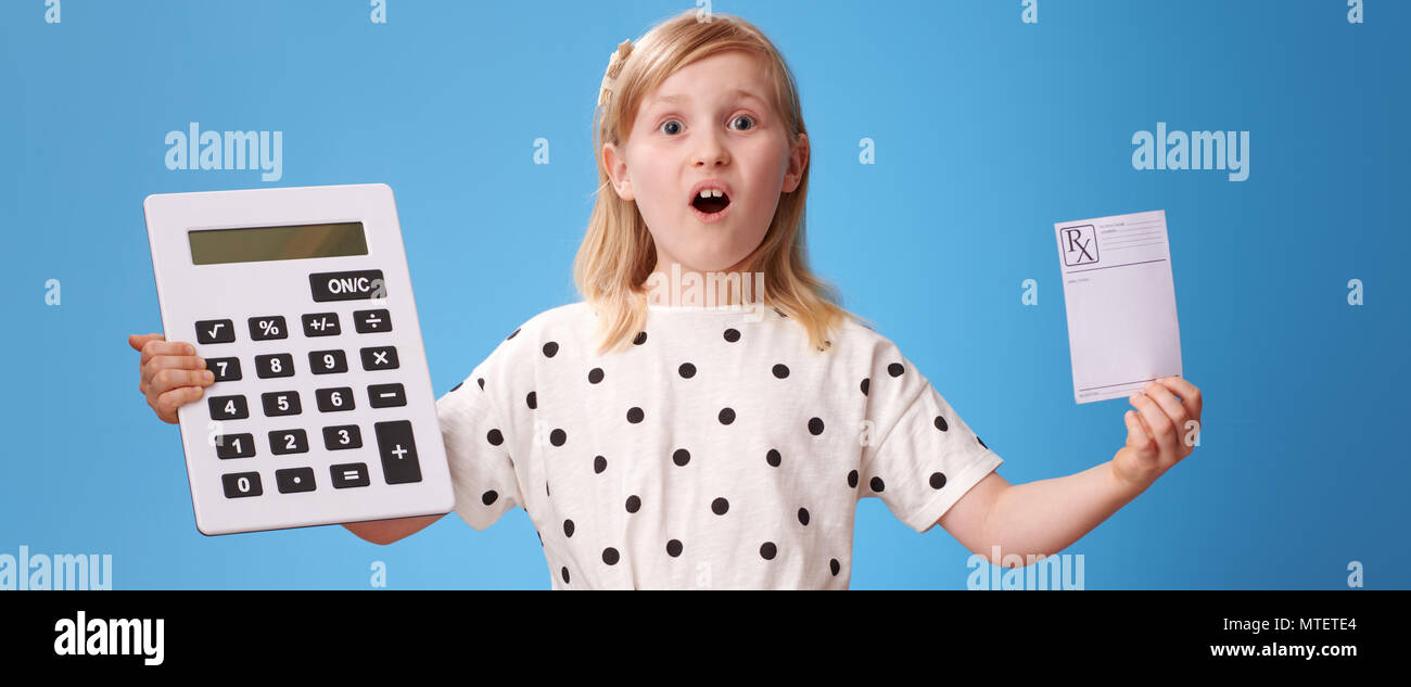 Sorpreso bambino moderno in pantaloni rossi che mostra la prescrizione e calcolatrice isolato su blu Foto Stock