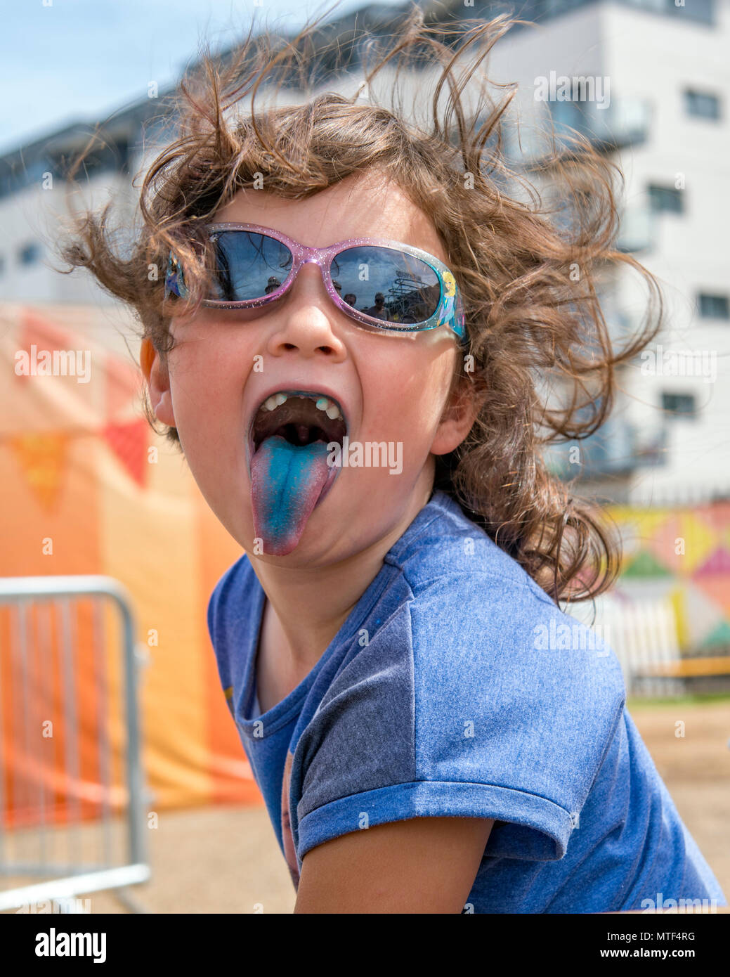 Cheeky giovane ragazza prendendo la sua linguetta blu colorata da un ghiaccio per lecca-lecca Foto Stock