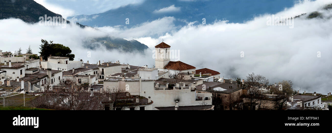 Il villaggio Alpujarran di Capileira con la sua chiesa cattolica, situato in alto sopra le nuvole nelle montagne della Sierra Nevada in Spagna in Andalusia. Foto Stock