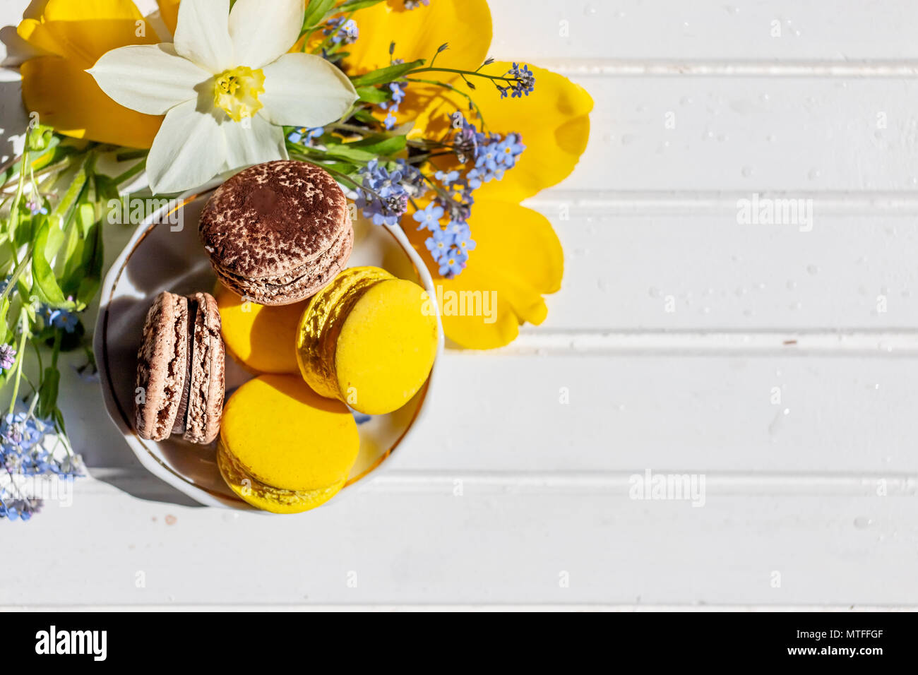 Macarons o amaretti dessert dolce bello mangiare. cioccolato e limone  Dessert su un bianco tavolo in legno.gustoso piatto da dessert di laici e  di narcisi e dimenticare-me-non fiori Foto stock - Alamy